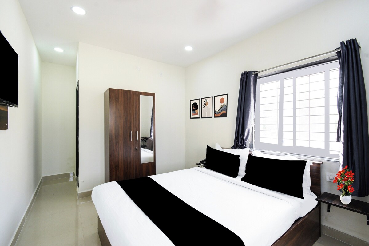 Una habitación de hotel con cama, armario, ventana con cortinas y televisor de pared.