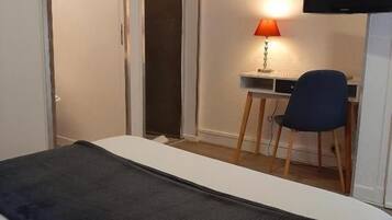 Habitación de hotel con una cama, un escritorio con una silla, un televisor y una puerta corrediza.