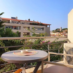 Un balcon avec une table ronde, une chaise et un bâtiment en arrière-plan.