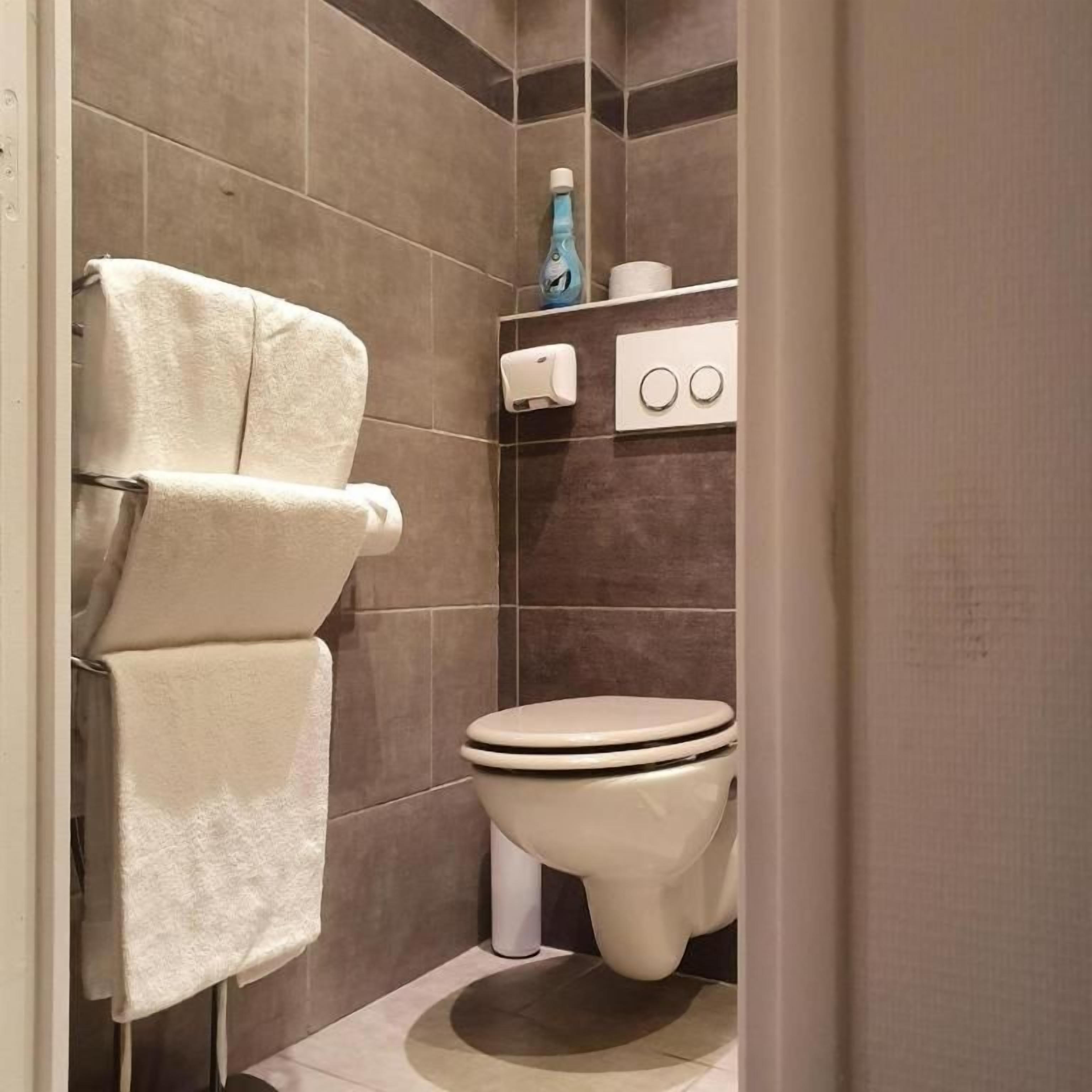 Een badkamer met toilet, handdoekhouder en een plank met toiletartikelen.