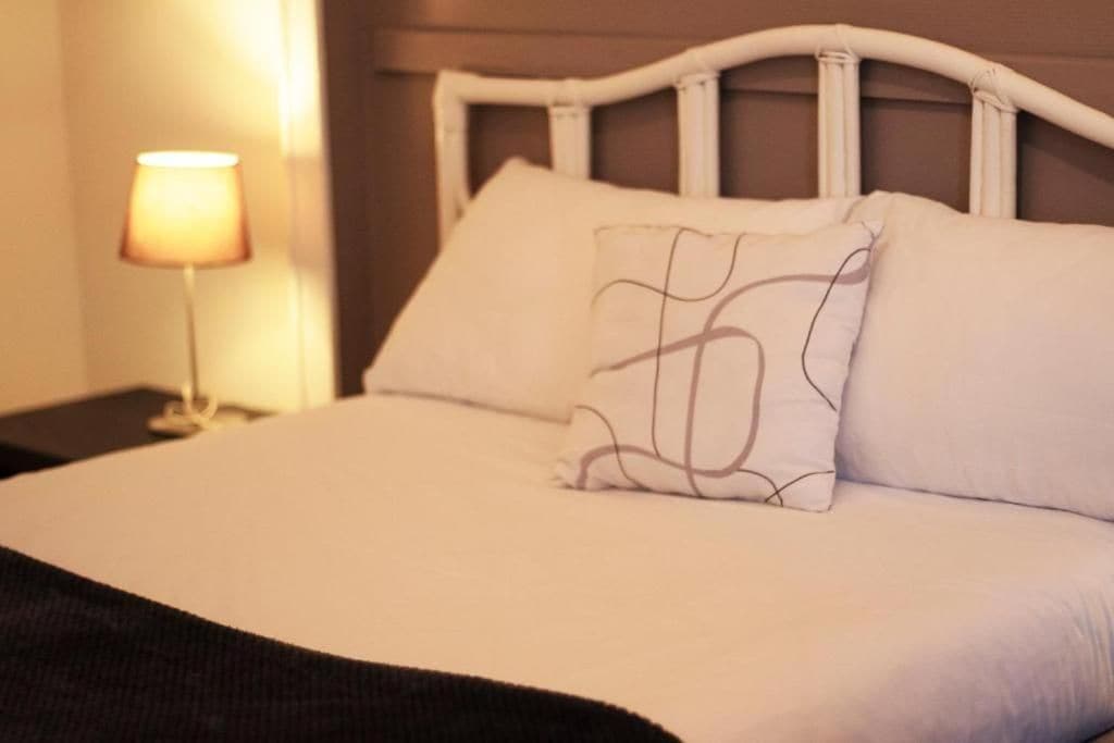 Een bed met een wit hoofdeinde en twee kussens, waarvan er een een ontwerp heeft.