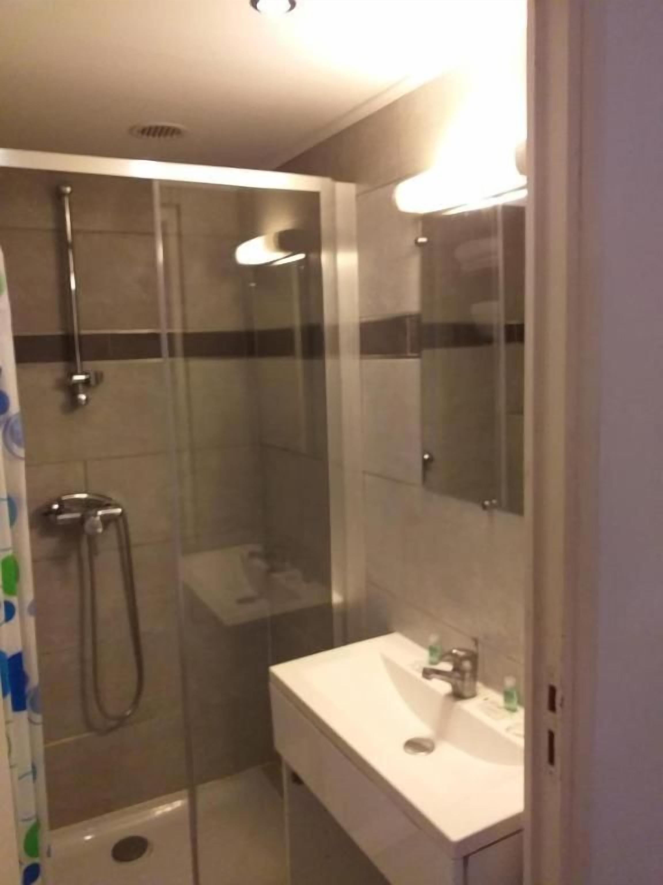 Ein modernes Badezimmer mit einer ein Glasfachraum-Dusche, einem weißen Waschbecken und einem Spiegel.