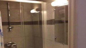 Een moderne badkamer met een douchecabine van glas, een witte wastafel en een spiegel.
