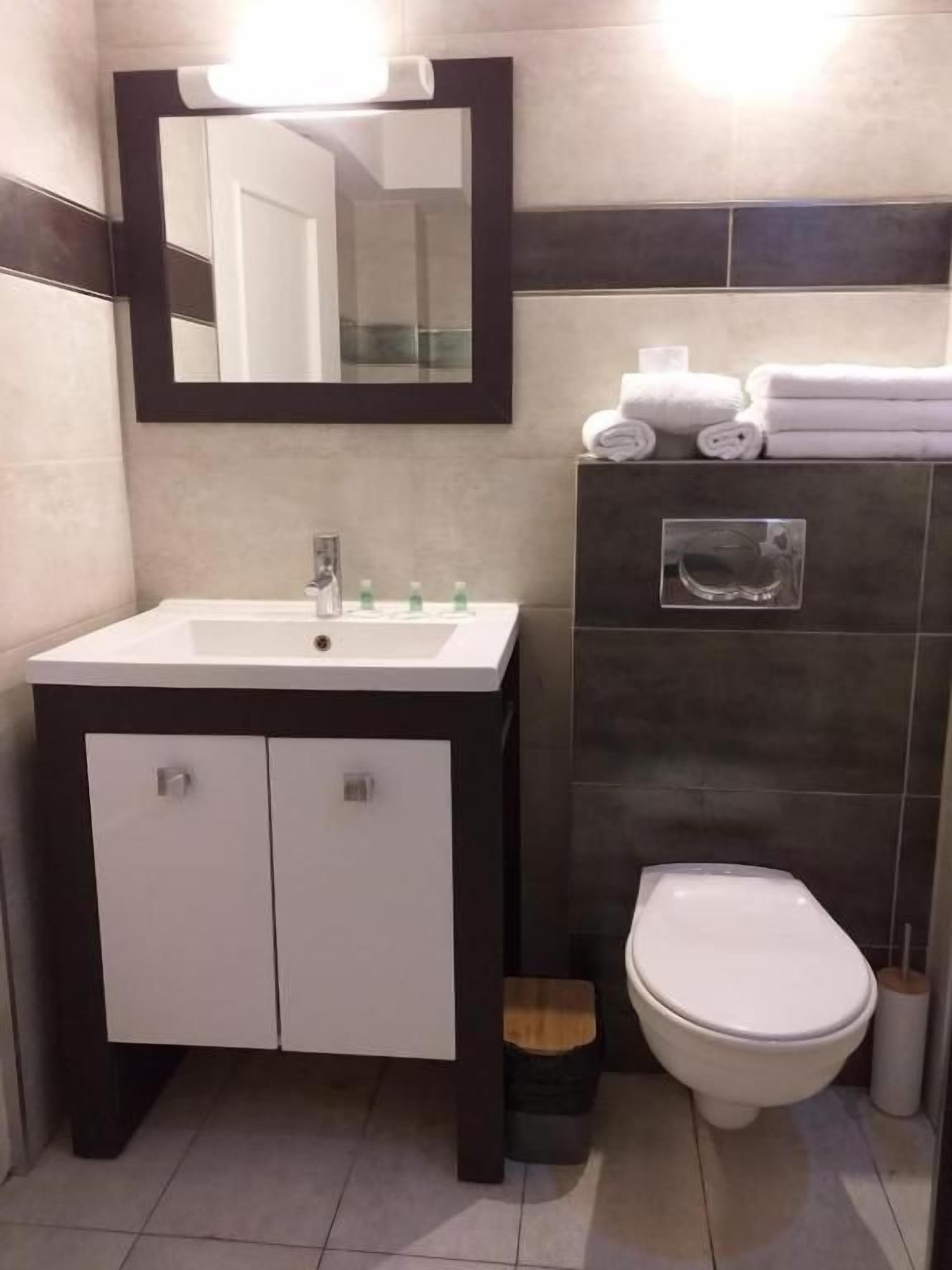 A bathroom with a white sink, a mirror, a toilet, and a towel rack.