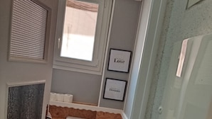 A compact bathroom with a toilet, a window, and two framed motivational quotes on the wall. - Lourdes: 5-Bedroom Duplex for 15 Guests, Central Location Near the Shrine (Lourdes)