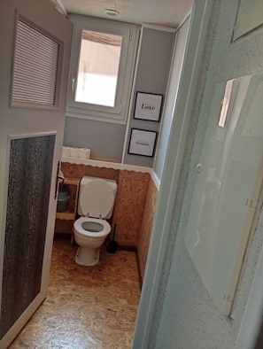 A compact bathroom with a toilet, a window, and two framed motivational quotes on the wall. - Lourdes: 5-Bedroom Duplex for 15 Guests, Central Location Near the Shrine (Lourdes)
