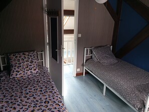 A room with two beds, one with a leopard print bedspread and the other with a patterned bedspread. - Lourdes: 5-Bedroom Duplex for 15 Guests, Central Location Near the Shrine (Lourdes)