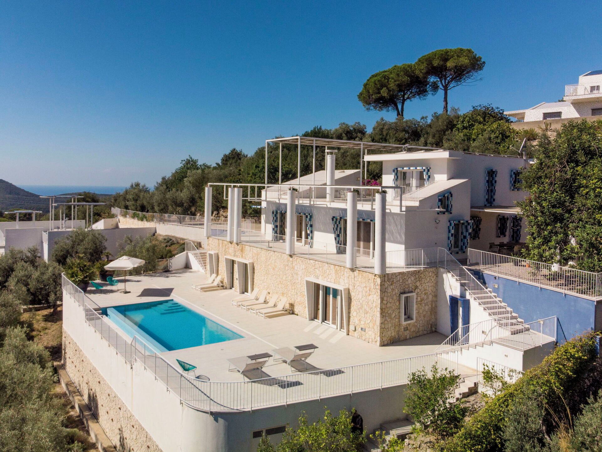 Eine moderne Villa mit Swimmingpool, mehreren Balkonen und Blick auf die umliegende Landschaft.