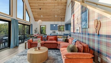 A spacious living room with a large sectional sofa, a round coffee table, and a view of the outdoors through large windows.