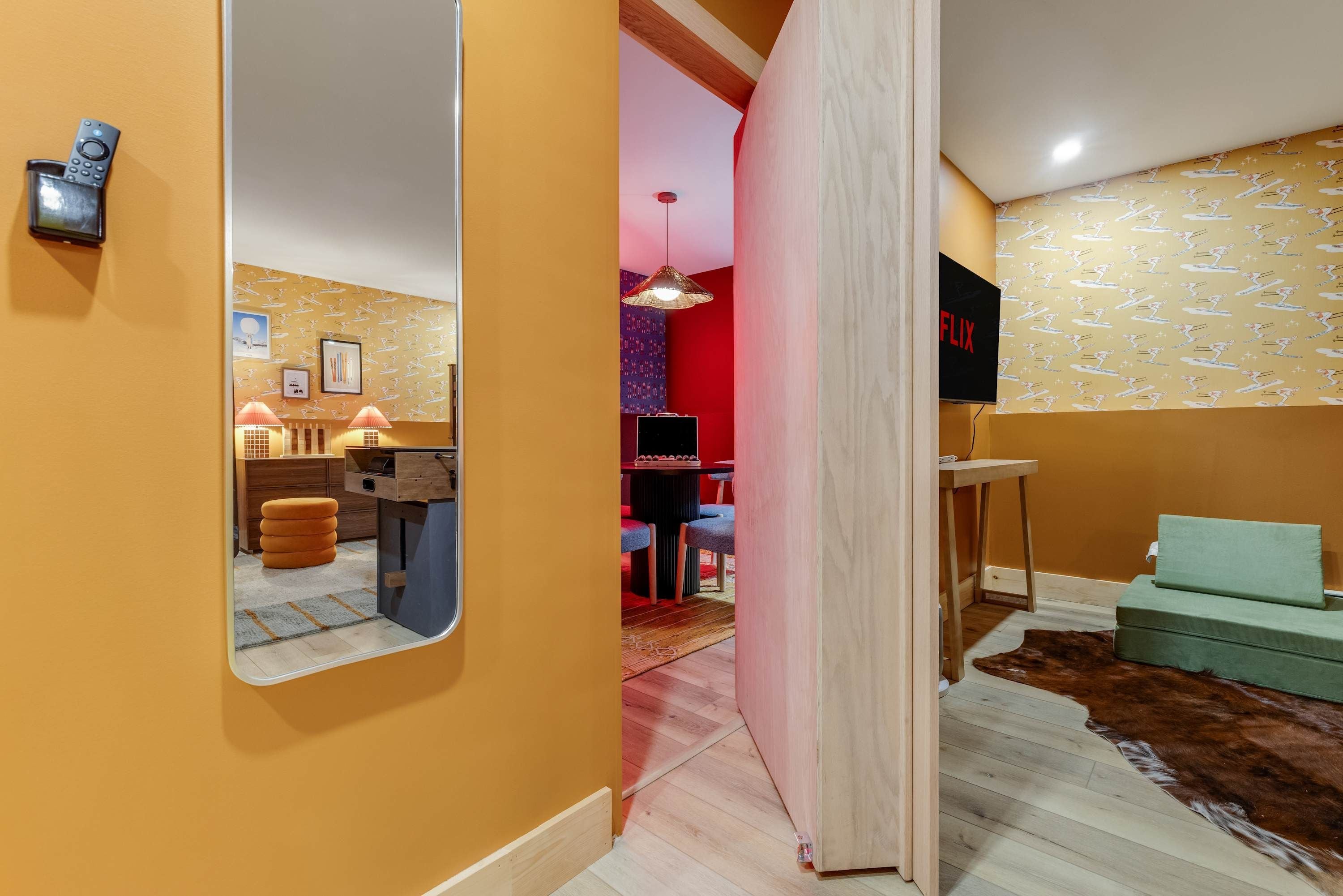 A modern interior with a wooden floor, a mirror, a television, and a patterned wall.