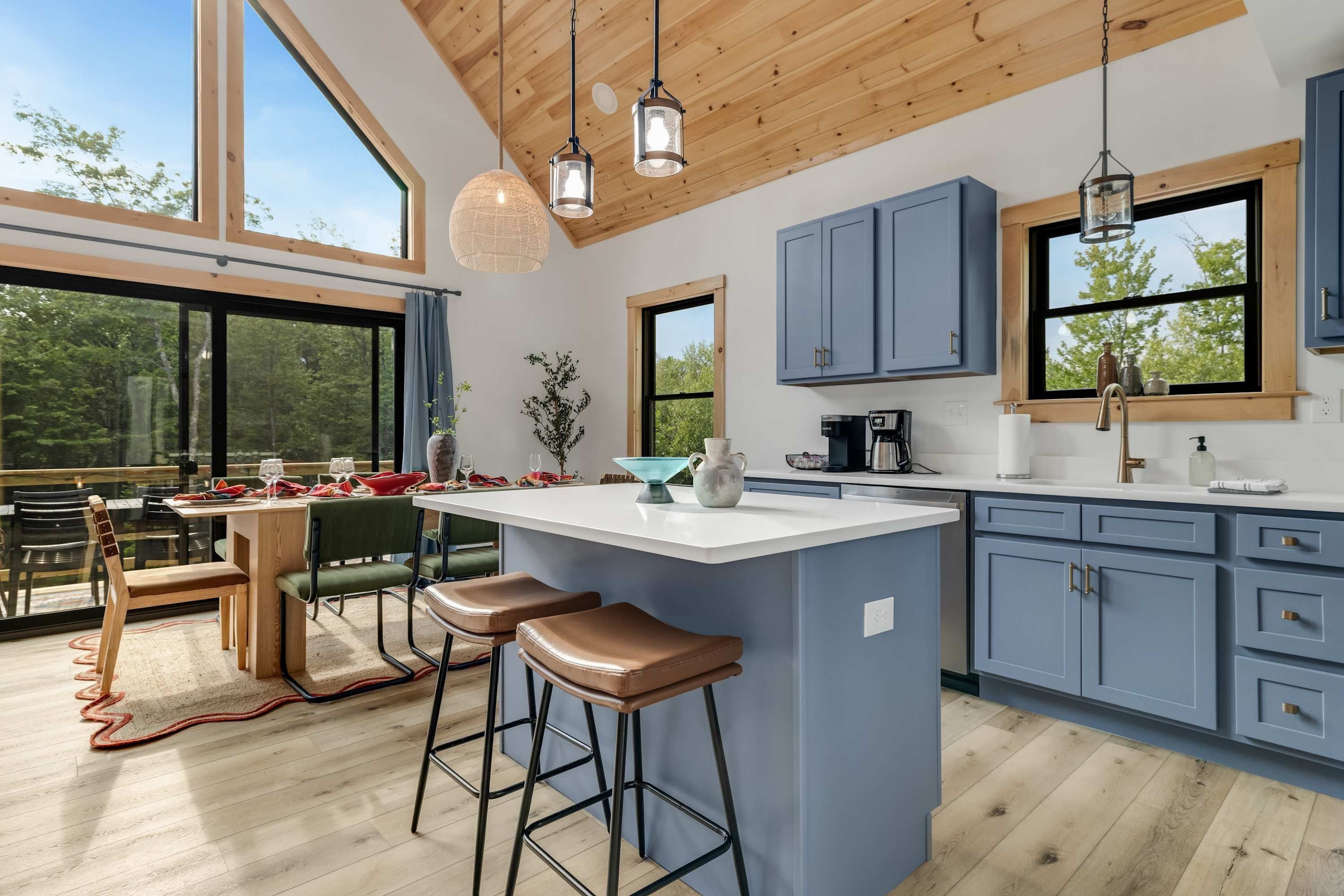 A modern kitchen with a large island, bar stools, and blue cabinets.