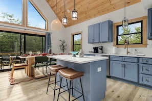 A modern kitchen with a large island, bar stools, and blue cabinets. - Close to Sunday River Hot Tub Sauna Cold Plunge (Bethel)