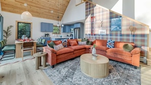 A modern living room with a wooden ceiling, a plaid-patterned wall, and a large sectional sofa. - Close to Sunday River Hot Tub Sauna Cold Plunge (Bethel)