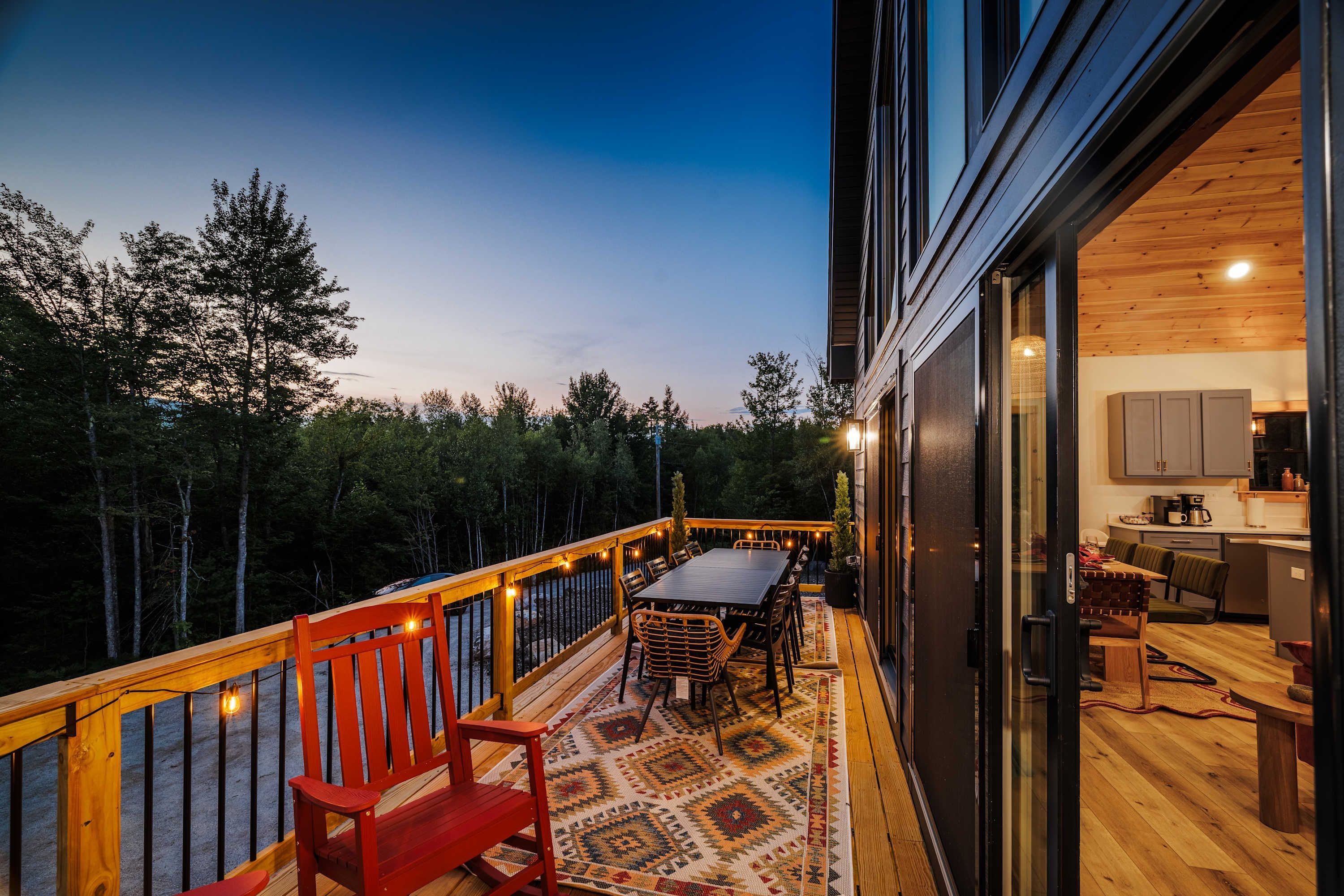 A deck with a table and chairs, a wooden bench, and a patterned rug.