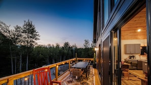 A deck with a table and chairs, a wooden bench, and a patterned rug. - Close to Sunday River Hot Tub Sauna Cold Plunge (Bethel)