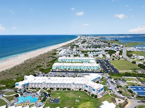 Un complejo turístico costero con varios edificios hoteleros, una playa y una zona de piscina.