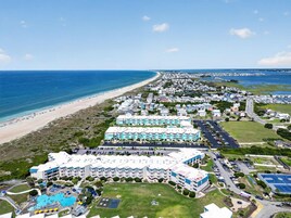 A coastal resort with multiple hotel buildings, a beach, and a swimming pool area.