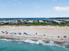 A coastal hotel with multiple buildings, a sandy beach, and a view of the ocean.