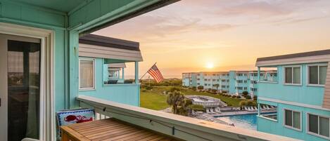A balcony with a view of a swimming pool and a building with an American flag.