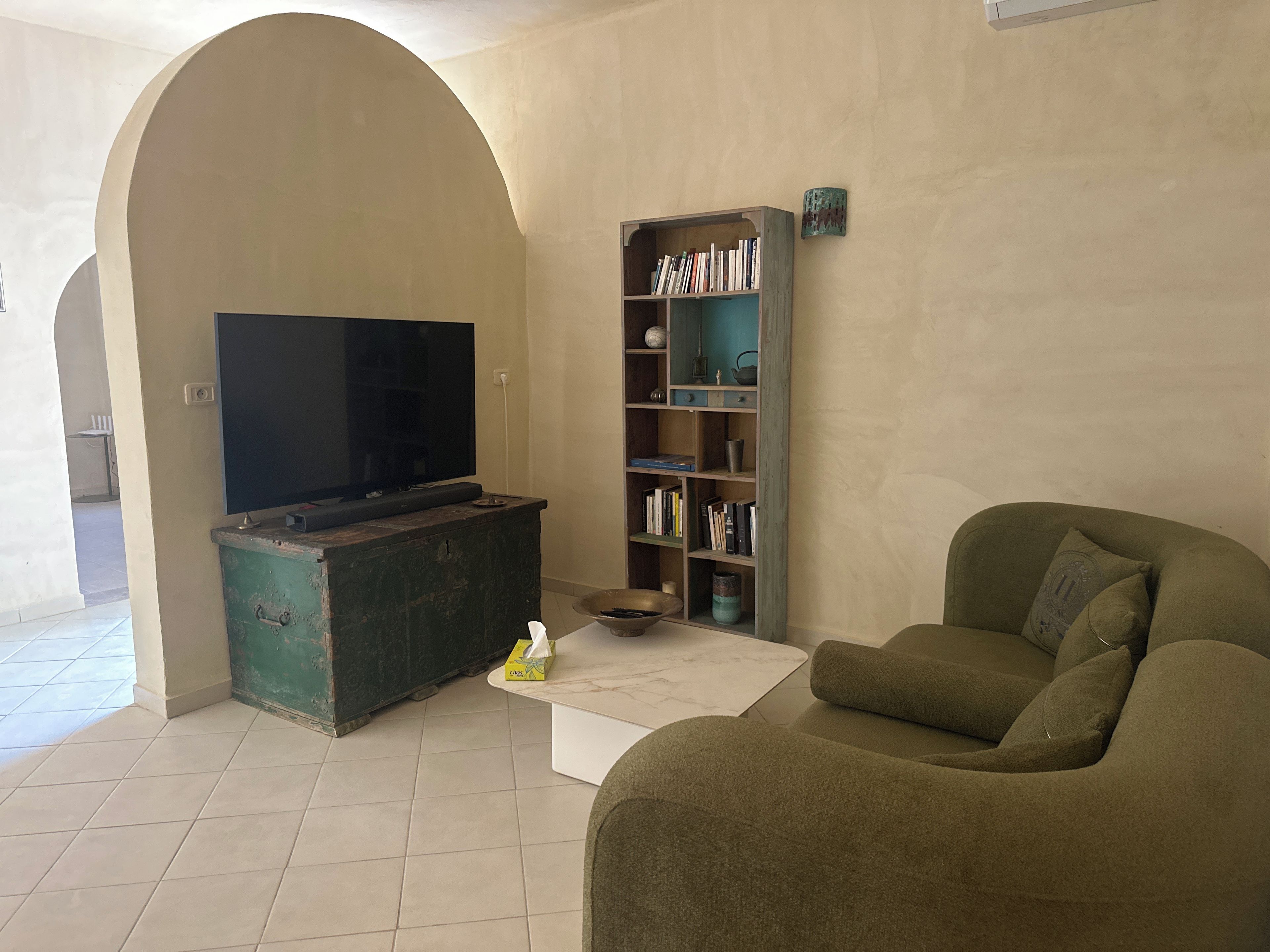 A living room with a television, a bookshelf, a sofa, and a coffee table.