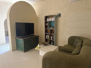 A living room with a television, a bookshelf, a sofa, and a coffee table.