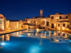 A nighttime view of a pool area with a reflection of the building and sky.