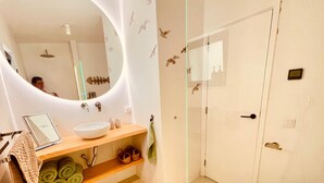 Une salle de bain avec un lavabo blanc, un miroir, un porte-serviettes et des toilettes.