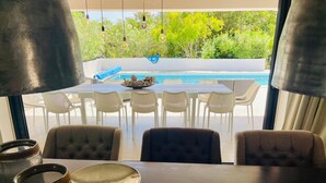 Un espace repas avec vue sur une piscine et des sièges d’extérieur.