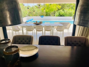 Spiseplads med udsigt til pool og udendørs møbler.