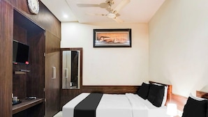 A hotel room with a bed, a wardrobe, a ceiling fan, a framed artwork, and a television. - Townhouse Sindhi Camp (Jaipur)