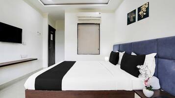A modern hotel room with a large bed, a flat-screen TV, a bedside table with a phone, and a wall-mounted air conditioning unit.