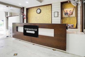 A reception desk with a sign reading 'TOWNHOUSE Company-Serviced' in a modern building with a clock and framed pictures on the wall. - Townhouse Bhopal DB City Mall (Bhopal)