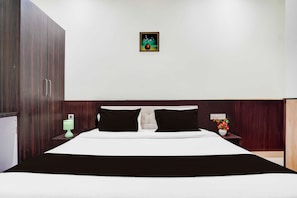 A hotel room with a large bed, two bedside tables, a nightstand, a wall-mounted power outlet, and a framed picture above the bed. - Townhouse Oak  Faizabad Road (Lucknow)
