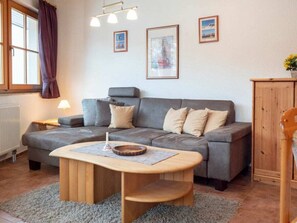 Ein gemütliches Wohnzimmer mit einer grauen Couch, einem Holztisch und einer Heizung.