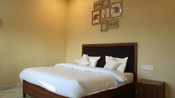 A neatly made bed with a wooden headboard in a room with cream walls.