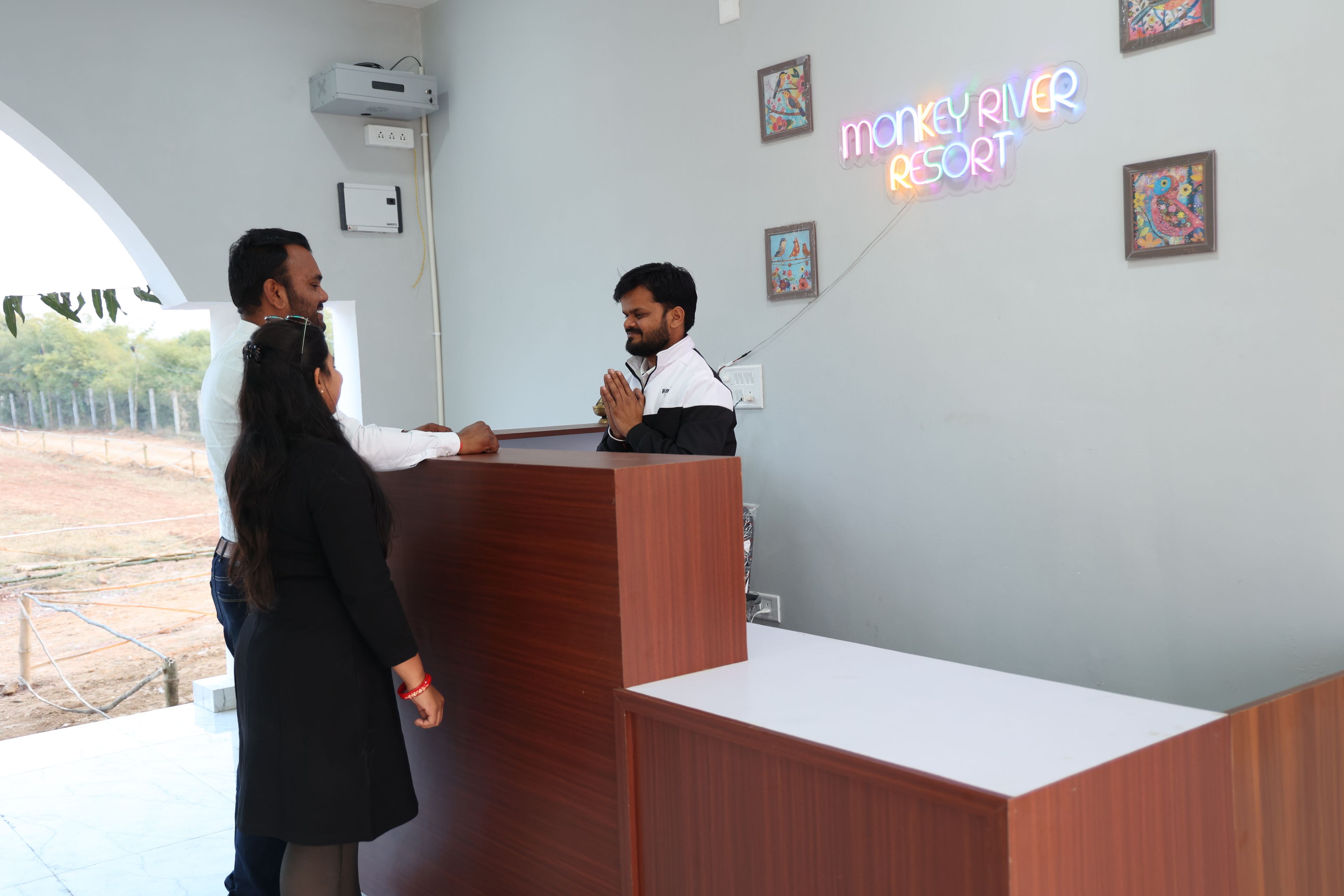 A reception desk with a neon sign, framed artwork on the wall, and a clear view of the outdoors.