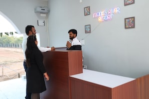 A reception desk with a neon sign, framed artwork on the wall, and a clear view of the outdoors. - Monkey River Resort  (Madla)