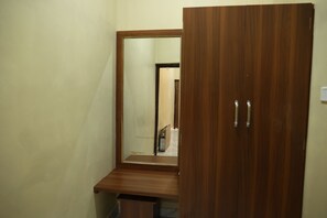 A wooden wardrobe with a mirror, a wooden bench, and a door with handles.