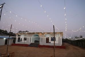 A building with a red base and white walls, surrounded by a dirt path and a fence. - Monkey River Resort  (Madla)