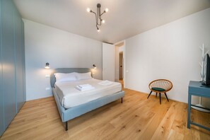A bedroom with a bed, bedside lamps, a chair, a desk, and a television. - An elegant, modern 70-square-meter apartment located on the fifth floor of a building (with an elevator, though not suitable for people with disabilities) near the city center.Ideal for two people, the property is situated just a short walk from the trai (Udine)