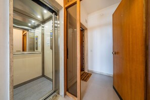 An elevator with a control panel, a wooden door, and a carpeted floor. - An elegant, modern 70-square-meter apartment located on the fifth floor of a building (with an elevator, though not suitable for people with disabilities) near the city center.Ideal for two people, the property is situated just a short walk from the trai (Udine)