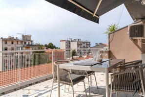 A balcony with a table and chairs, a view of the city, and a plant. - An elegant, modern 70-square-meter apartment located on the fifth floor of a building (with an elevator, though not suitable for people with disabilities) near the city center.Ideal for two people, the property is situated just a short walk from the trai (Udine)