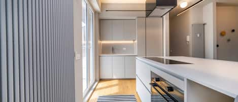 Una cocina moderna con estufa integrada, armarios blancos y una alfombra a rayas.