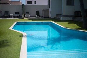A swimming pool with a surrounding grassy area and lounge chairs. - Apartamento Naru (San Pedro del Pinatar) (San Pedro del Pinatar)