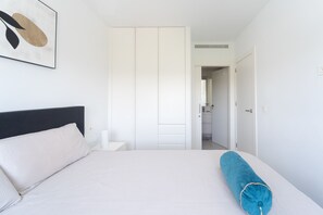 A bedroom with a bed, a nightstand, a white wardrobe, and a bathroom visible through an open door. - Apartamento Naru (San Pedro del Pinatar) (San Pedro del Pinatar)