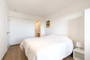 Ein Schlafzimmer mit einem Bett, einem Nachttisch, einer Lampe und einer Tür zu einem Badezimmer.