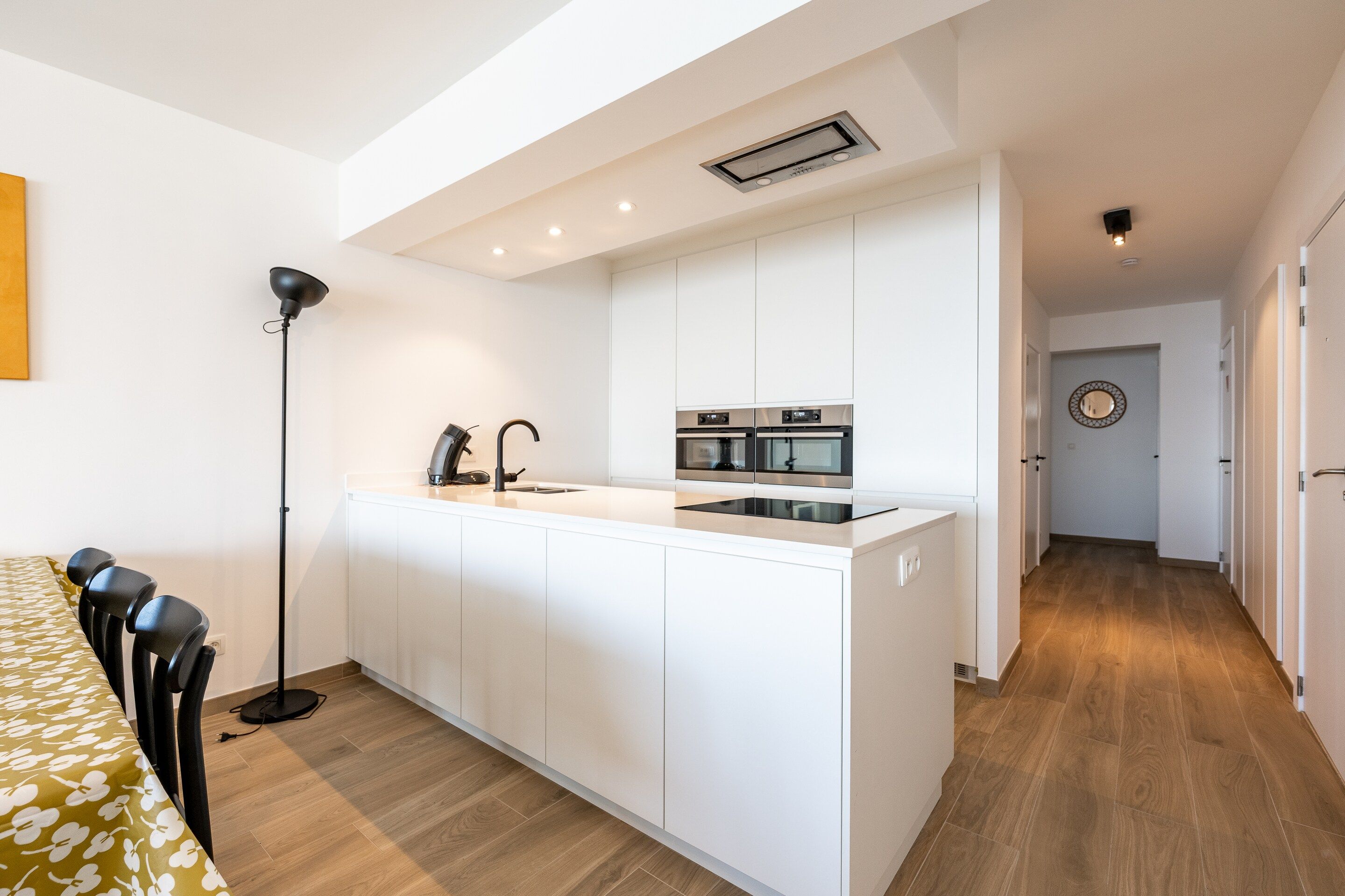 A modern kitchen with white cabinetry, a central island, and built-in appliances.