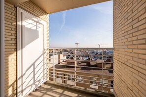 A balcony with a view of a cityscape, featuring a metal railing and a door. - Apartment in Blankenberge With Sea Views (Blankenberge)