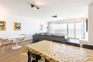 A modern living room with a sofa, a dining table with chairs, and artwork on the walls. - Apartment in Blankenberge With Sea Views (Blankenberge)