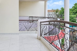 Ein Balkon mit weiß gefliestem Boden und einem Metallgeländer mit aufwendigen Verzierungen.